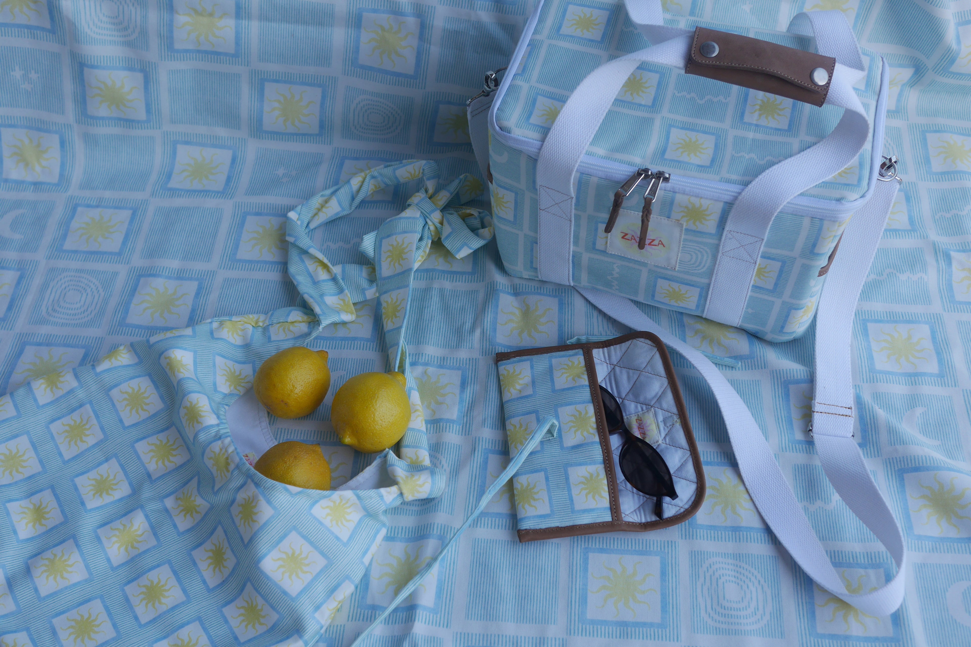 ZAZZA Blue Cooler Bag styled with picnic collection, a pair of sunglasses and lemons 