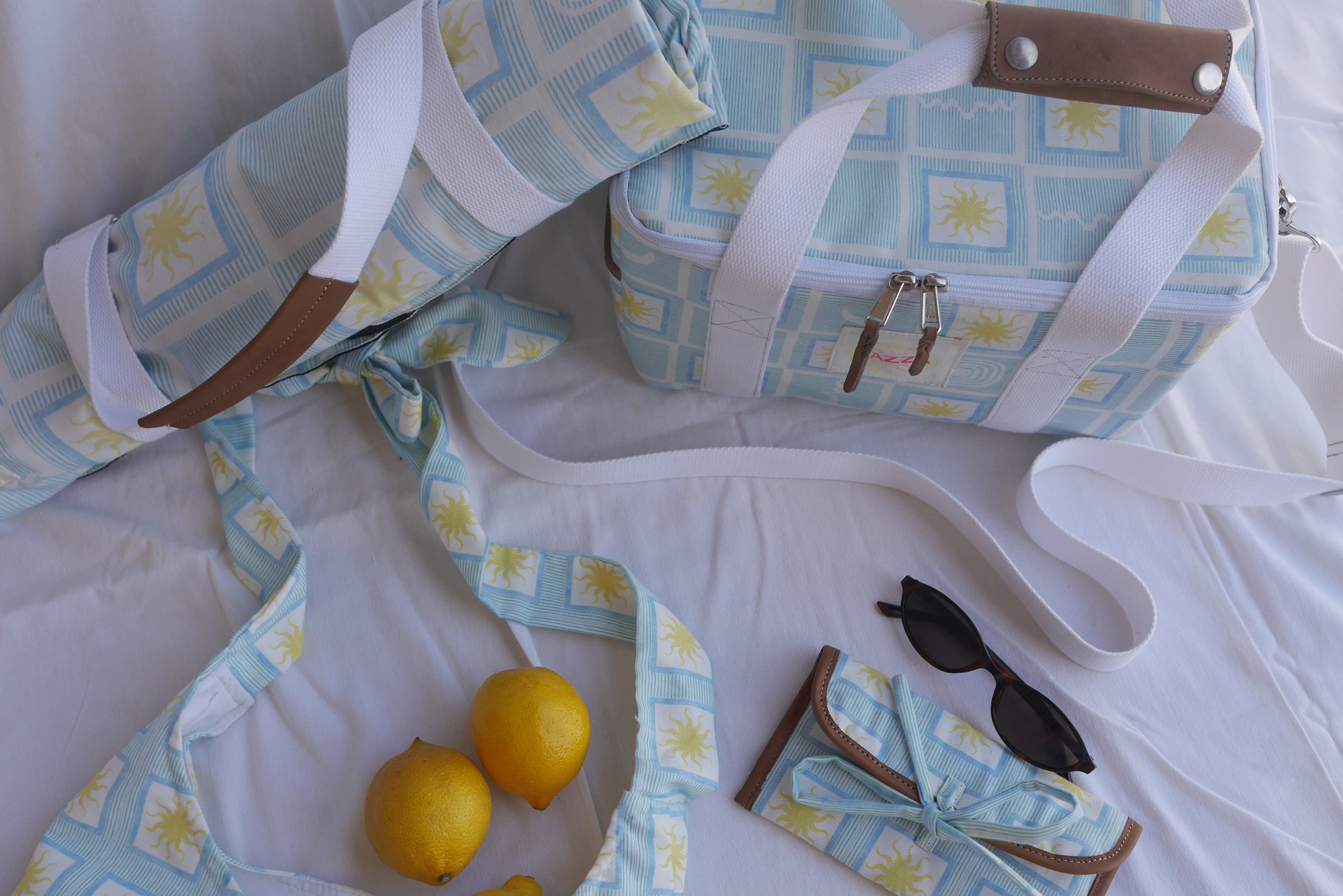 ZAZZA blue picnic collection, styled on a white background with lemons & a pair of sunglasses