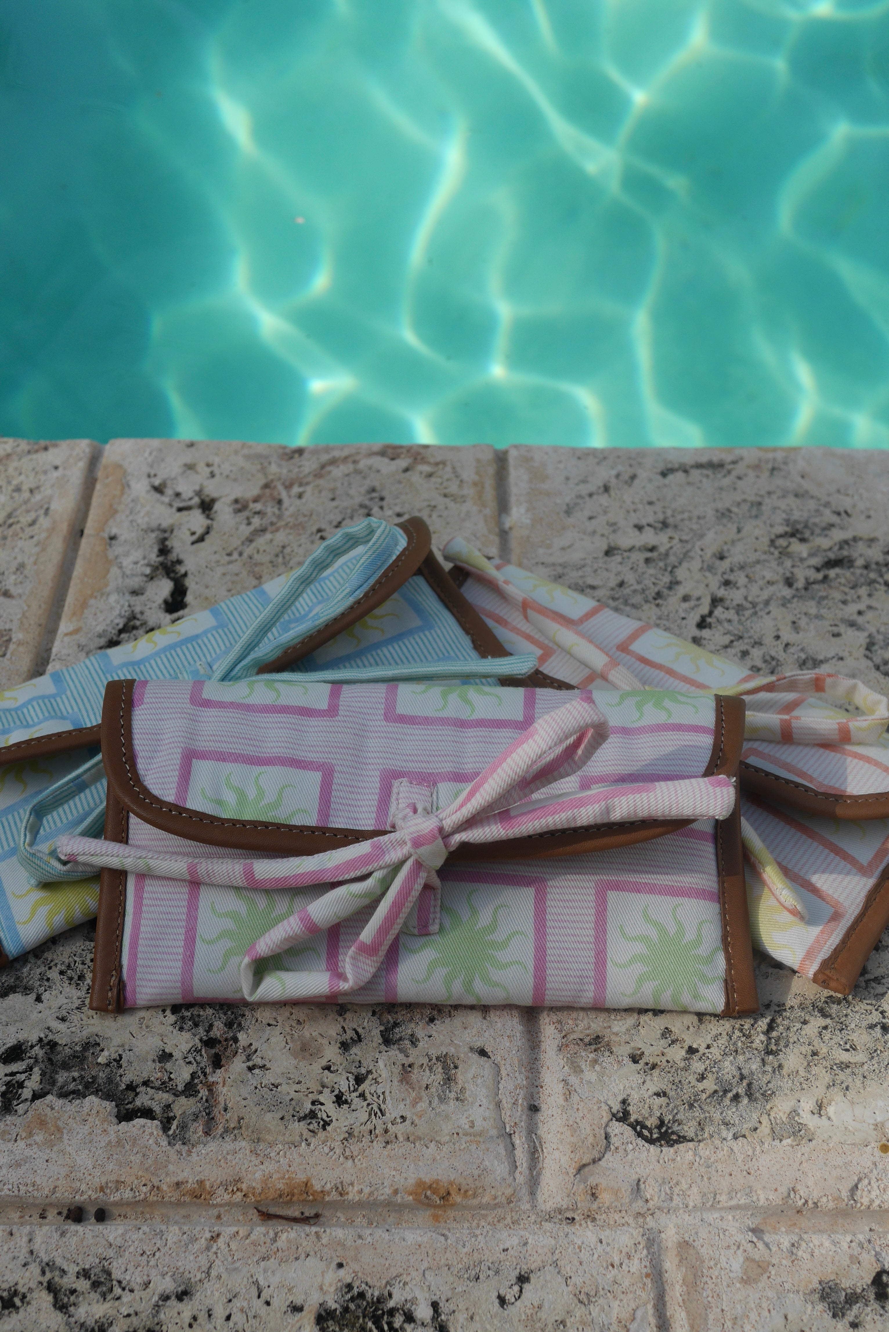All ZAZZA sunglasses cases on a stone surface near a pool.