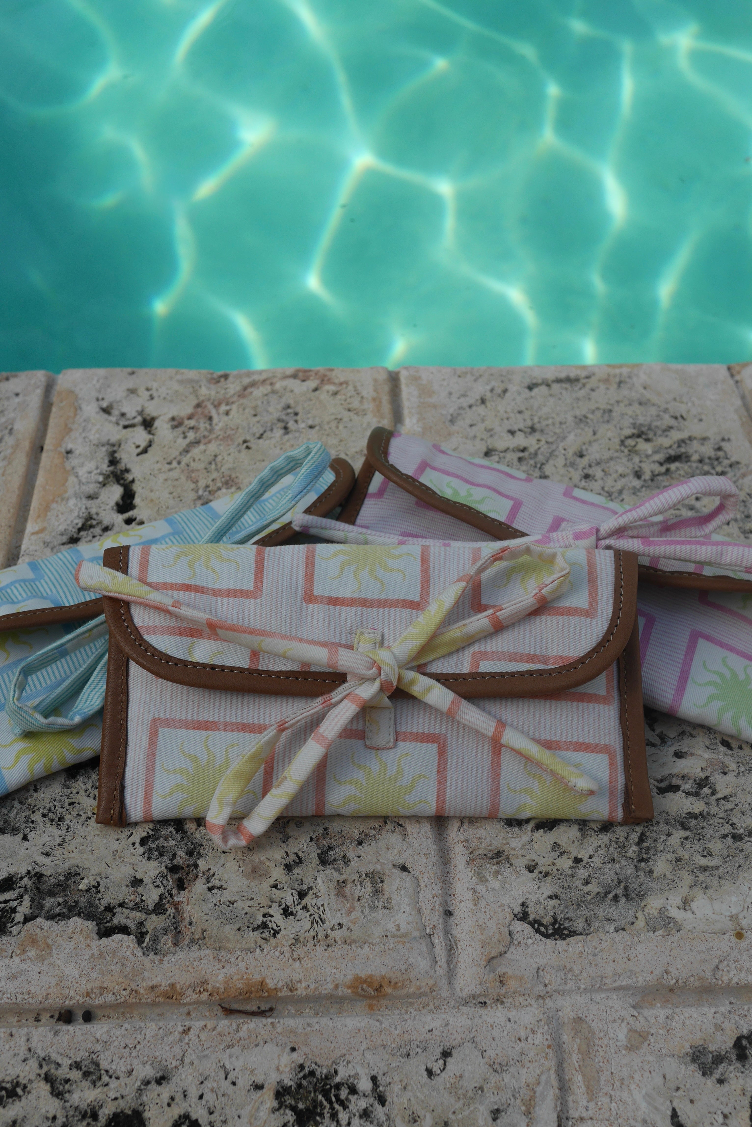 All ZAZZA sunglasses cases on a stone surface near a pool