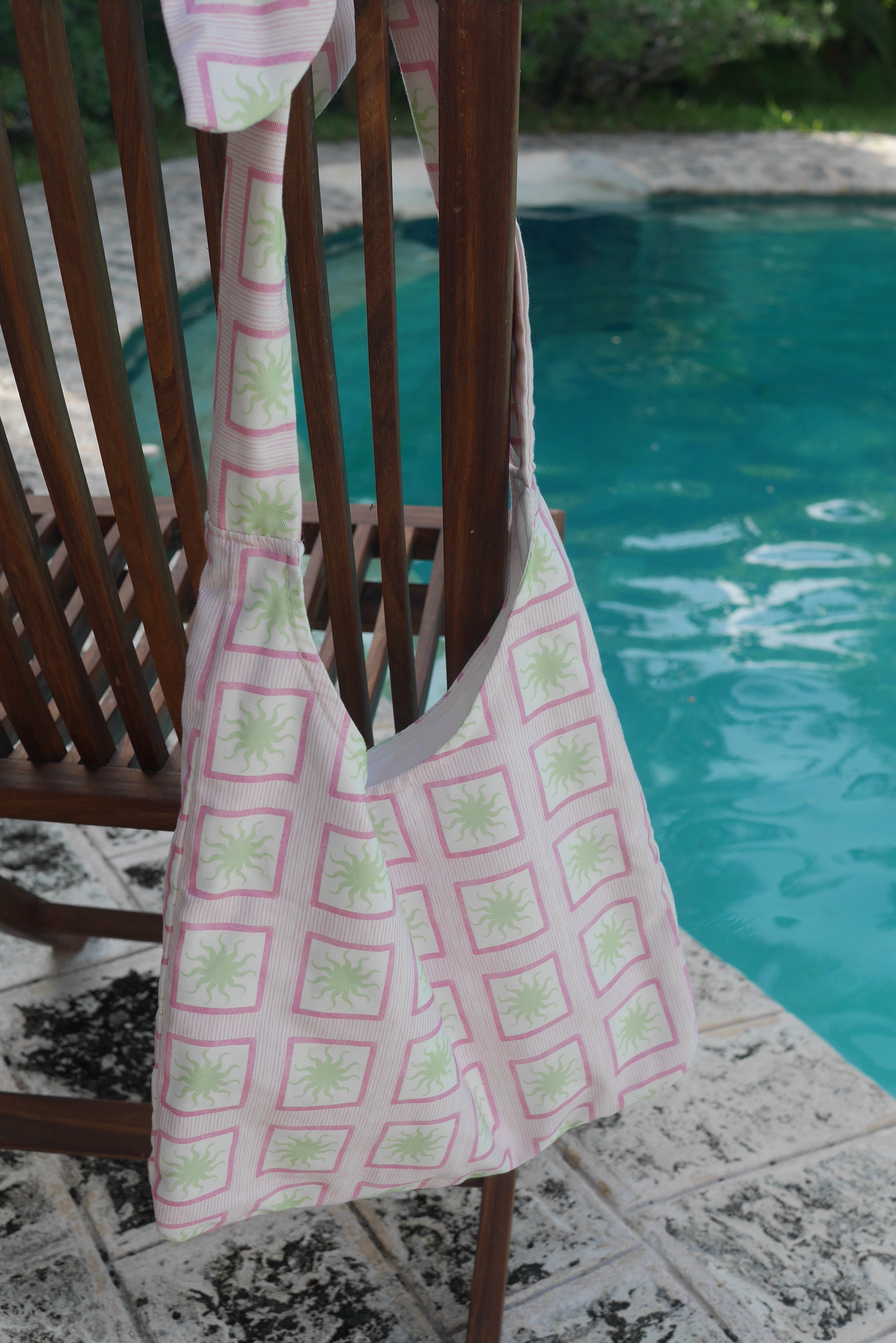 Pink ZAZZA Tote bag hanging on a chair by a pool