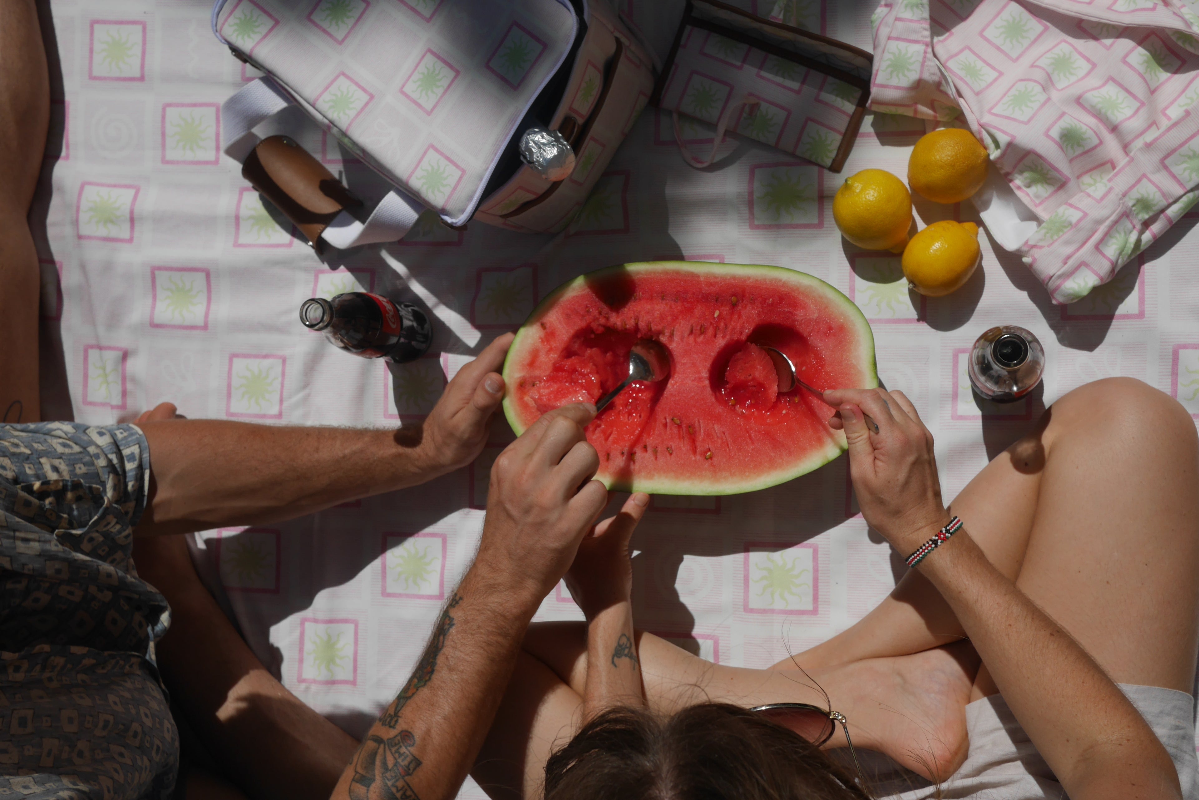 Two people sharing a watermelon , coca cola with the ZAZZA pink picnic collection