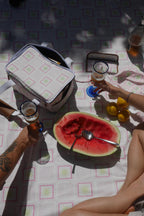 People enjoying a casual picnic with drinks and a watermelon on the ZAZZA pink picnic blanket with the collection 