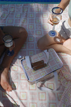 Two people enjoying  drinks  on with ZAZZA red cooler bag & picnic blanket 