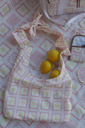 Flat lay image of ZAZZA Red  tote bag with lemons on a matching fabric background (picnic blanket) & other products from the picnic collection