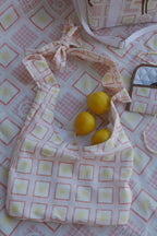 Flat lay image of ZAZZA Red  tote bag with lemons on a matching fabric background (picnic blanket) & other products from the picnic collection